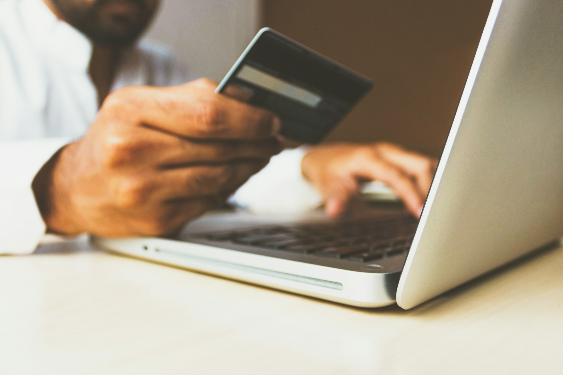 person holding a credit card and using a laptop